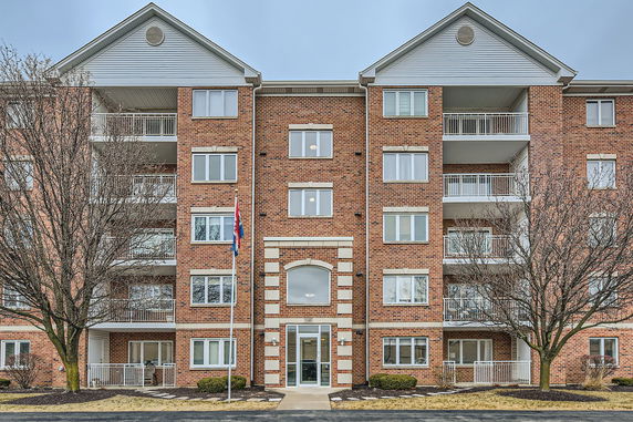 Front view of a multi-story brick apartment building with balconies.