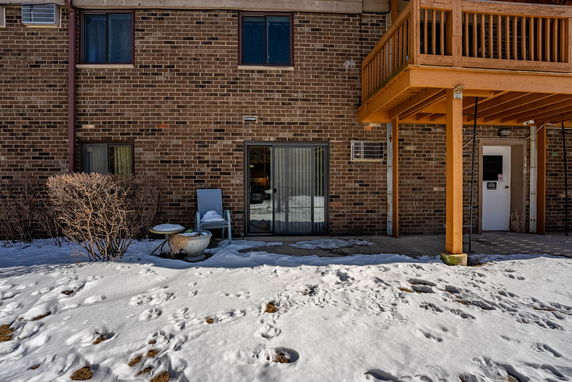 Front view of a brick building with a balcony and sliding glass door.