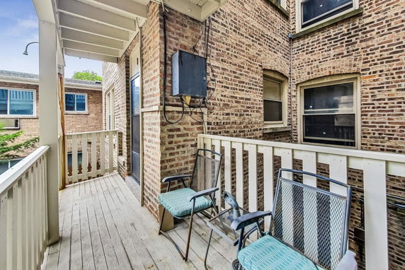 View of a narrow balcony with brick walls and outdoor chairs.