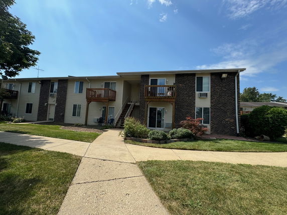 Front view of a two-story apartment building with balconies and brick facade.