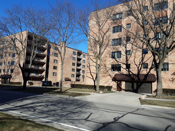 Front view of a multi-story brick apartment building with balconies.