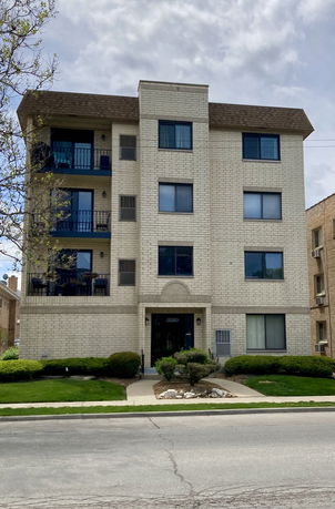 Front view of a four-story apartment building with balconies.