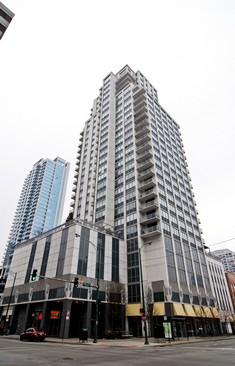 Front view of a tall, multi-story residential building on a city street corner.