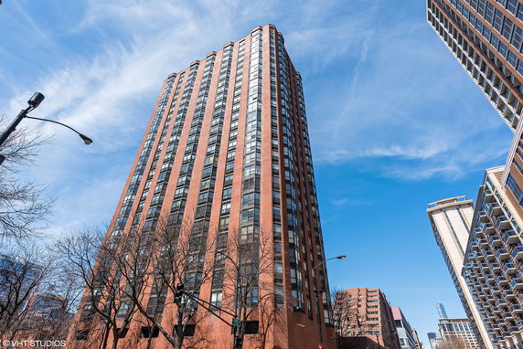 Front view of a tall multi-story building with a brick facade and numerous windows.