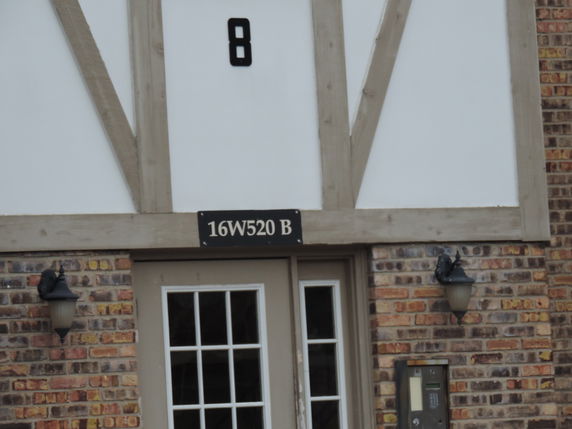 Front view of a brick building entrance with a door and number signage.