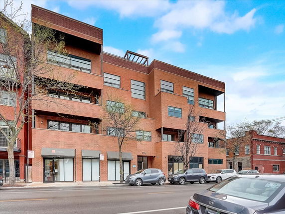 Front view of a multi-story brick building with large windows and a modern design.
