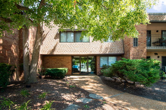 Front view of a brick two-story building with large windows and a walkway leading to the entrance.