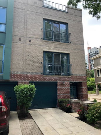 Front view of a multi-story brick building with garage and driveway.