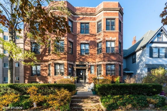 Front view of a multi-story brick building with rectangular windows and an entrance in the center.
