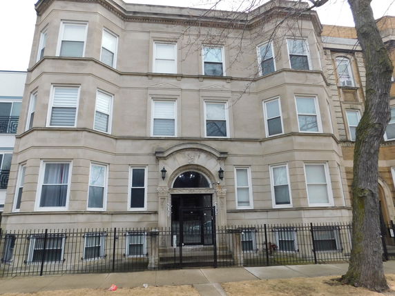 Front view of a three-story residential building with a detailed entrance and multiple windows.