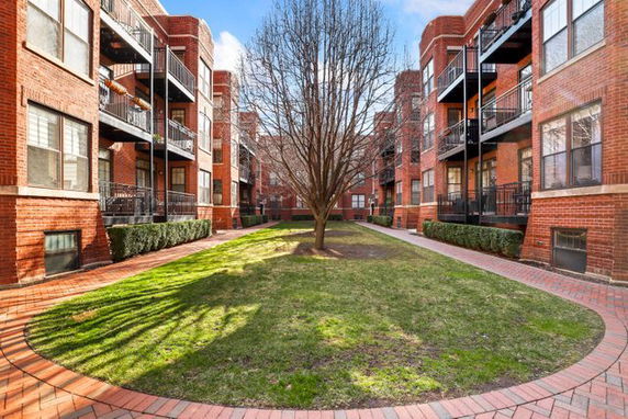 View of multiple brick apartment buildings with balconies facing a grassy courtyard.