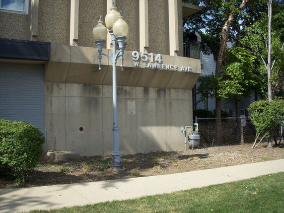 Front view of a building with a streetlamp and address displayed on the facade.