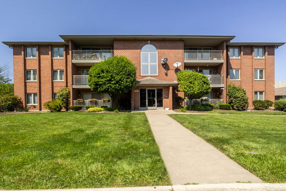Front view of a multi-story brick apartment building with balconies.