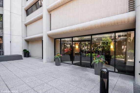 Front view of a modern building with large glass entrance and decorative planters.