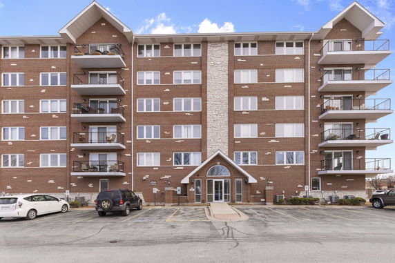 Front view of a multi-story brick building with balconies and a central entrance.