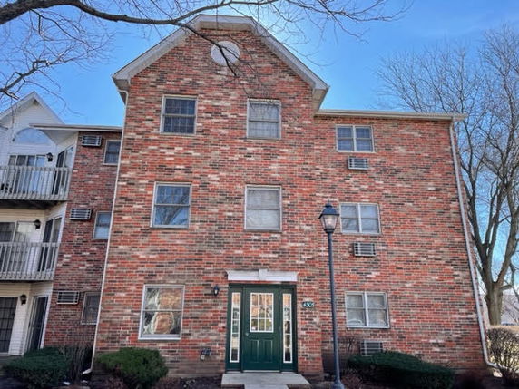Front view of a multi-story brick apartment building with visible windows and a central entrance.
