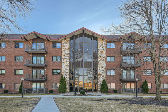 Front view of a multi-story brick apartment building with balconies and a central glass section.