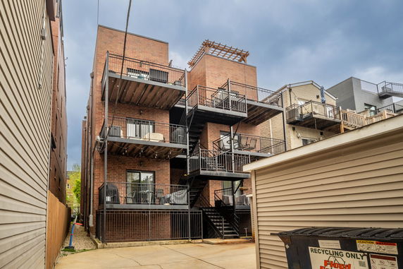 Rear view of a multi-story brick apartment building with multiple balconies and outdoor stairs.