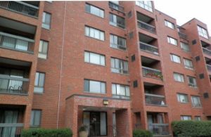 Front view of a multi-story brick apartment building with balconies.