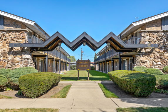 Front view of a two-story condominium building with stone accents and a central courtyard.