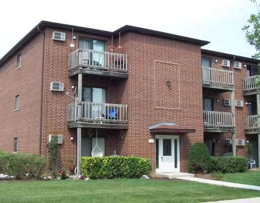 Front view of a three-story brick apartment building with balconies.