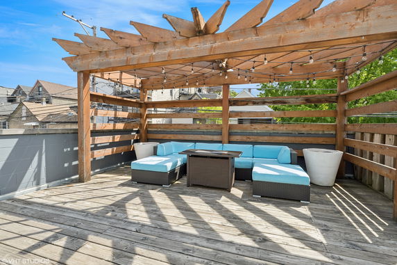 Rooftop deck with wooden pergola and outdoor seating area.