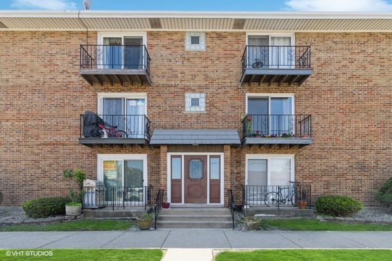 Front view of a multi-story brick apartment building with balconies.