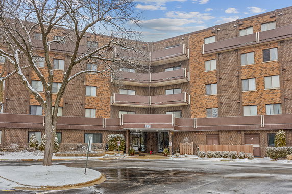 Front view of a four-story brick apartment building with multiple balconies.