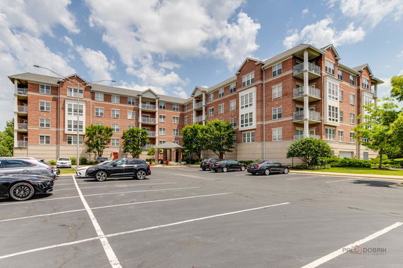 Front view of a multi-story apartment building with a parking area.