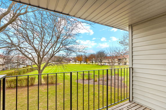 Panoramic view from a balcony overlooking a grassy area with trees.