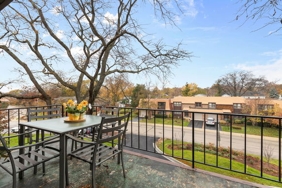 View from a balcony showing a street with houses and trees.