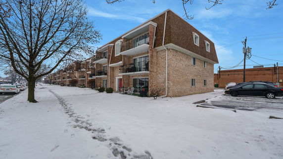 Front view of a multi-story brick apartment building with balconies.