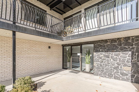 Front view of a building entrance with balcony and stone accent wall.