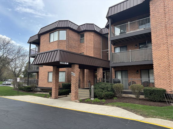Front view of a multi-story brick apartment building with balconies.
