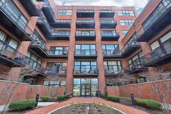 Front view of a multi-story brick apartment building with balconies.