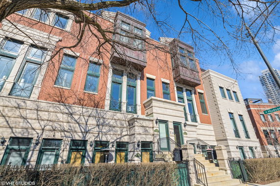 Front view of a multi-story red brick building with multiple windows and stairs leading to entrances.