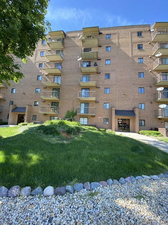 Front view of a multi-story brick apartment building with balconies.