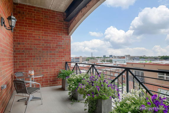 Balcony with brick wall and outdoor seating overlooking urban surroundings.