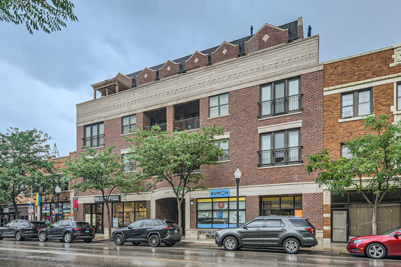 Front view of a multi-story brick building with commercial spaces on the ground floor.