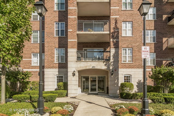 Front view of a multi-story brick building with balconies and entrance.