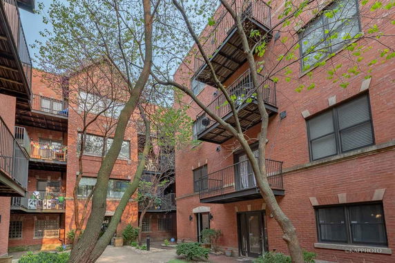 View of a brick apartment building with multiple balconies and windows.