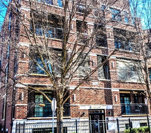 Front view of a multi-story building with brick exterior and balconies.