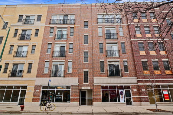 Front view of a multi-story commercial and residential building with brick facade and balconies.