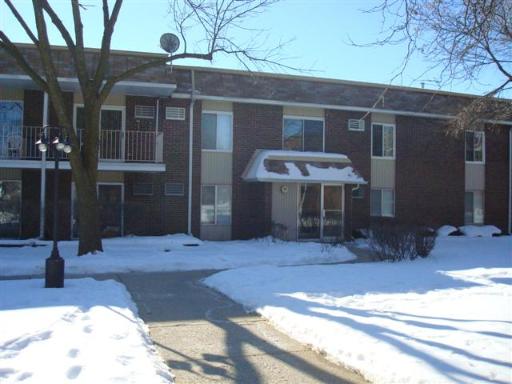 Front view of a brick apartment building with a snow-covered entrance.