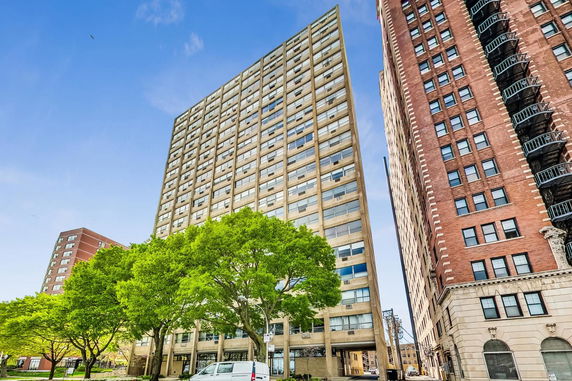 Front view of a tall apartment building with large windows.