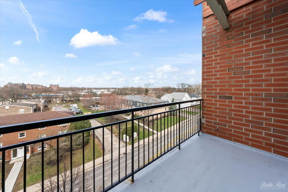 View from a balcony overlooking a residential neighborhood with roads and buildings.