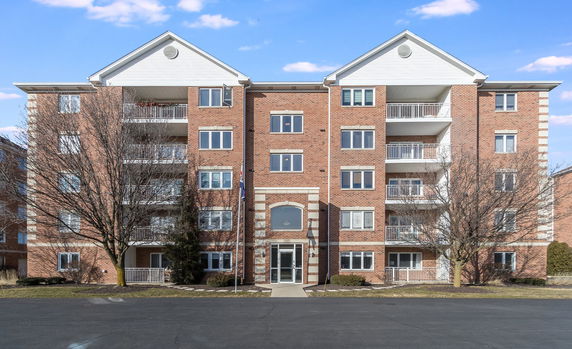 Front view of a multi-story brick apartment building with balconies.