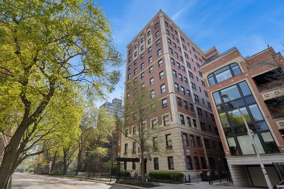 Front view of a multi-story brick building with large windows and a street view.