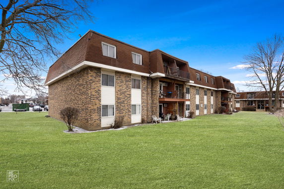 Side view of a multi-story brick residential building with balconies.