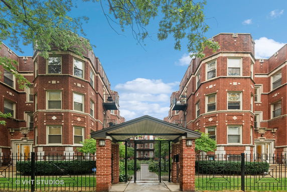 Front view of a symmetrical brick apartment building entrance with gated access.
